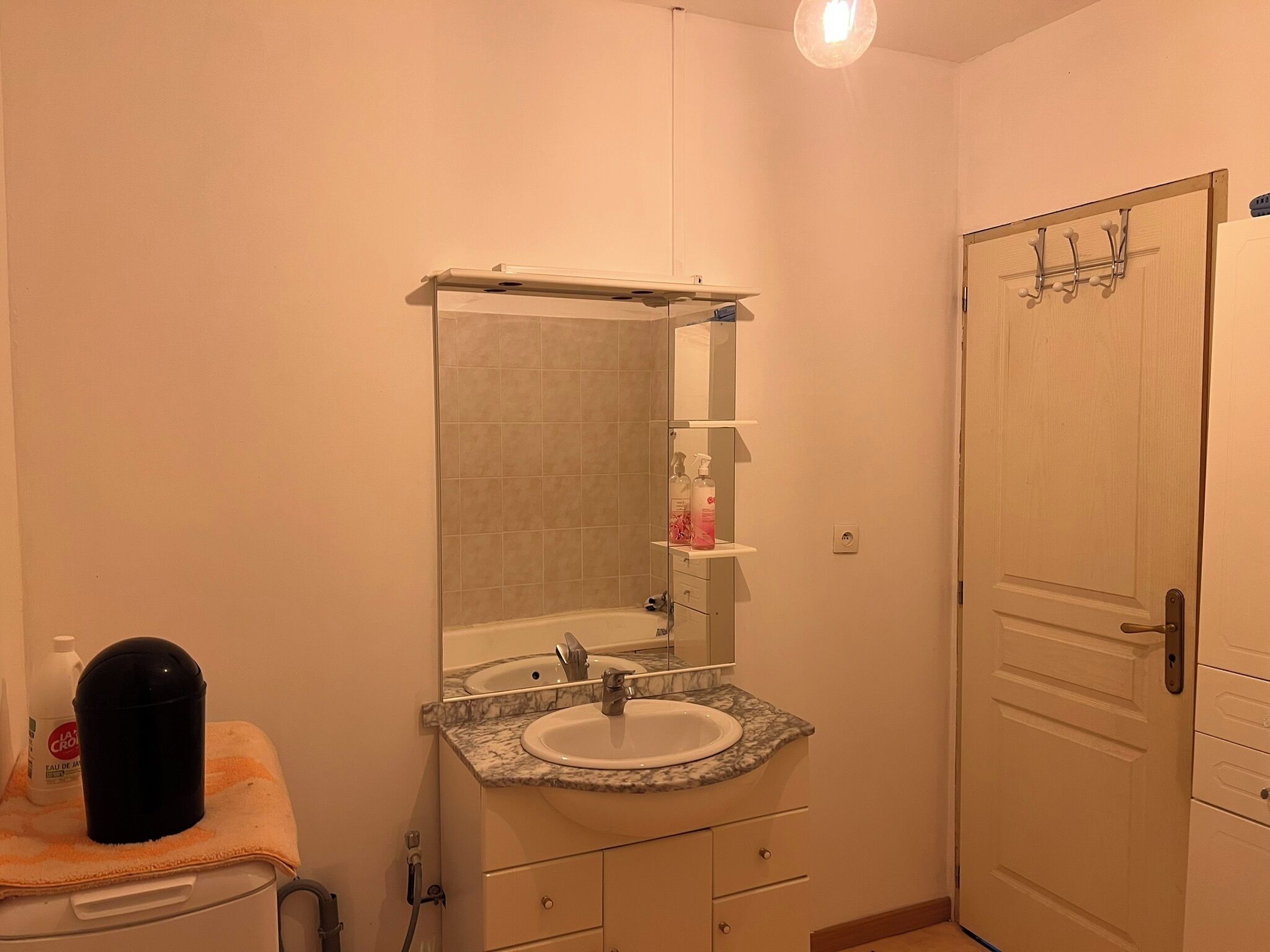 A bathroom with a sink, mirror, towel, and a door.