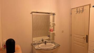 A bathroom with a sink, mirror, towel, and a door.