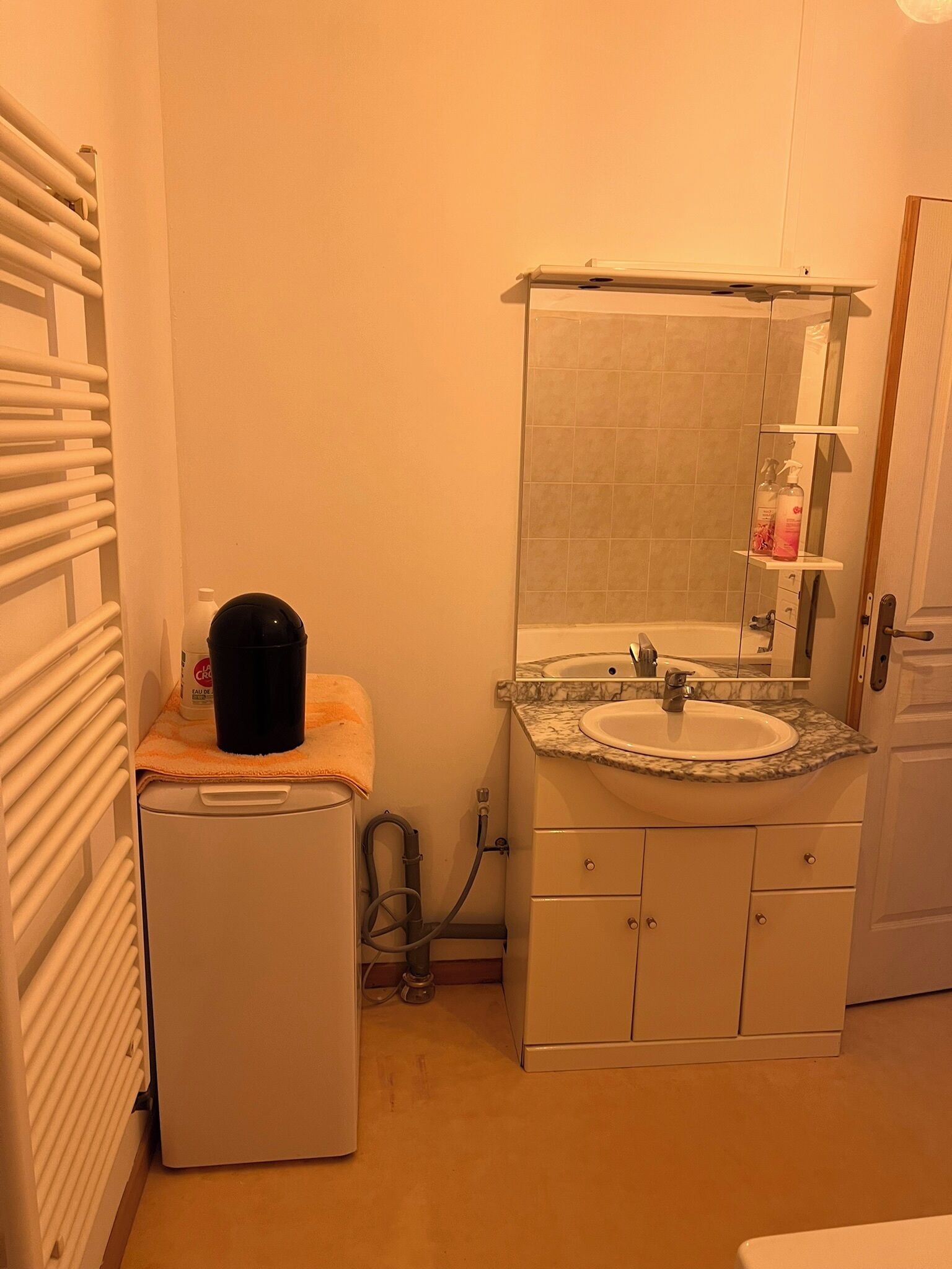 A compact bathroom with a sink, mirror, and a small heater.