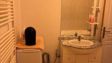 A compact bathroom with a sink, mirror, and a small heater.