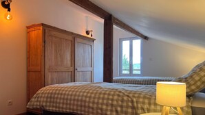 Un dormitorio con cama, lámpara de noche, armario y ventana.