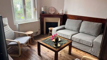 A living room with a sofa, armchairs, a coffee table, a fireplace, and a clock on the wall.