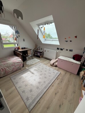 Een kinderkamer met een hoogslaper, bureau en een groot raam.