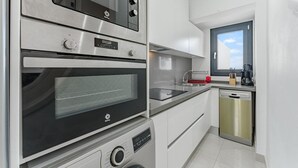 Μια σύγχρονη κουζίνα με συσκευές από ανοξείδωτο ατσάλι, πλυντήριο πιάτων και ένα παράθυρο με θέα.