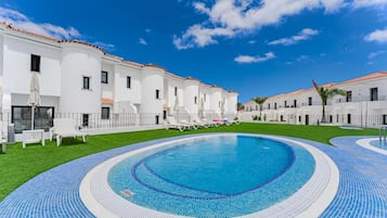 Una piscina al aire libre, sombrillas, tumbonas