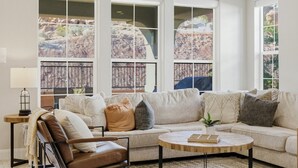 A living room with a sofa, a coffee table, a chair, and large windows with a view of rocky terrain. - Game loft, Nerf Wars, Resort Pool, Lazy River & Waterslide • Near Zion (Washington)