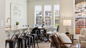 A kitchen with a dining area, bar stools, a table set for dining, a bar area, and a view of the outdoors through large windows. - Game loft, Nerf Wars, Resort Pool, Lazy River & Waterslide • Near Zion (Washington)