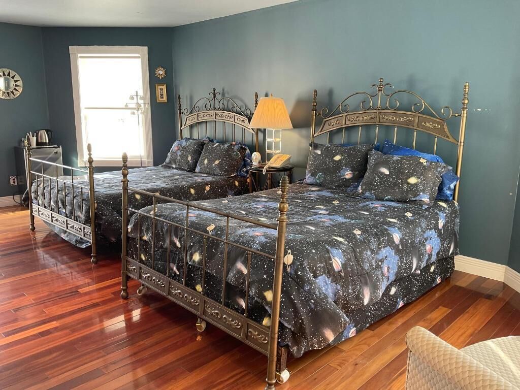A bedroom with a double bed, a side table, a lamp, and a dresser.