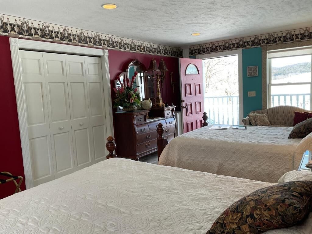 Une chambre avec deux lits, une commode, un miroir et une porte donnant sur un balcon.