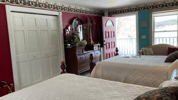 A bedroom with two beds, a dresser, a mirror, and a door leading to a balcony.