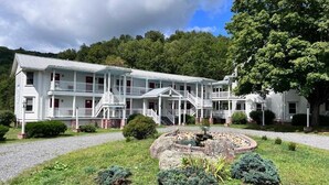 A large white building with multiple balconies and a central courtyard with a fountain. - Mountain Quest Inn (Marlinton)