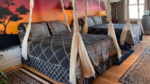 A bedroom with two beds, a canopy bed, a mural, and a giraffe statue. - Mountain Quest Inn (Marlinton)
