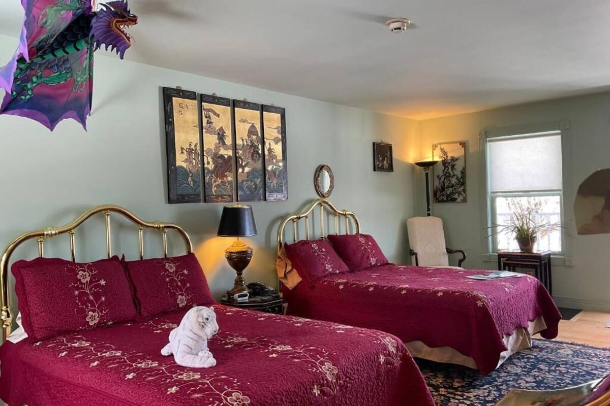 A room with two beds, a dragon decoration, and traditional artwork on the wall.