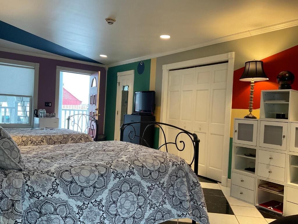 A bedroom with a bed, a TV, a wardrobe, and a door.