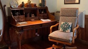 A wooden desk with drawers, a lamp, and a chair with a patterned cushion. - Mountain Quest Inn (Marlinton)