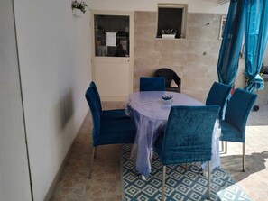 Een eetruimte met een tafel, stoelen, een raam en een deur.