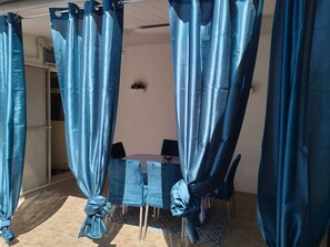 A room with a table and chairs, a curtain, and a small plant on the wall. - Mery Giò vacation home in San Pietro in Bevagna suitable for families and groups (San Pietro In Bevagna)