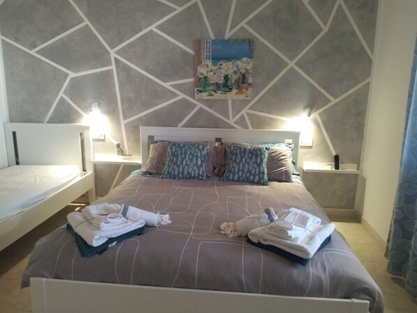 A hotel room with a bed, two bedside tables, a painting on the wall, and towels on the bed. - Mery Giò vacation home in San Pietro in Bevagna suitable for families and groups (San Pietro In Bevagna)