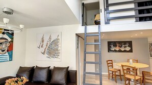 Ein modernes Wohnzimmer mit einer Couch, einem Esstisch mit Stühlen und Kunstwerken an den Wänden.