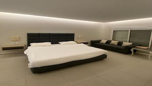 A modern bedroom with a large bed, a sofa, a bedside table, and a window. - Lemon Beach Chalet in Durrat Al Arous (درة العروس)