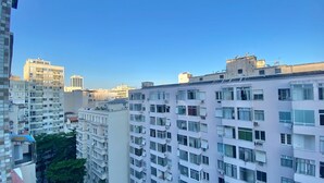 Een hoog appartementencomplex met veel balkons, grote ramen en een helderblauwe lucht.