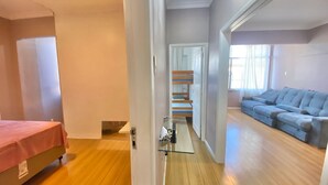 Een kamer met een bed, een bank, een trap en een deur naar een andere kamer.