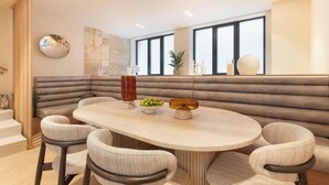 Uma área de refeições moderna com uma mesa redonda, assentos em um banco acolchoado e um vaso decorativo.