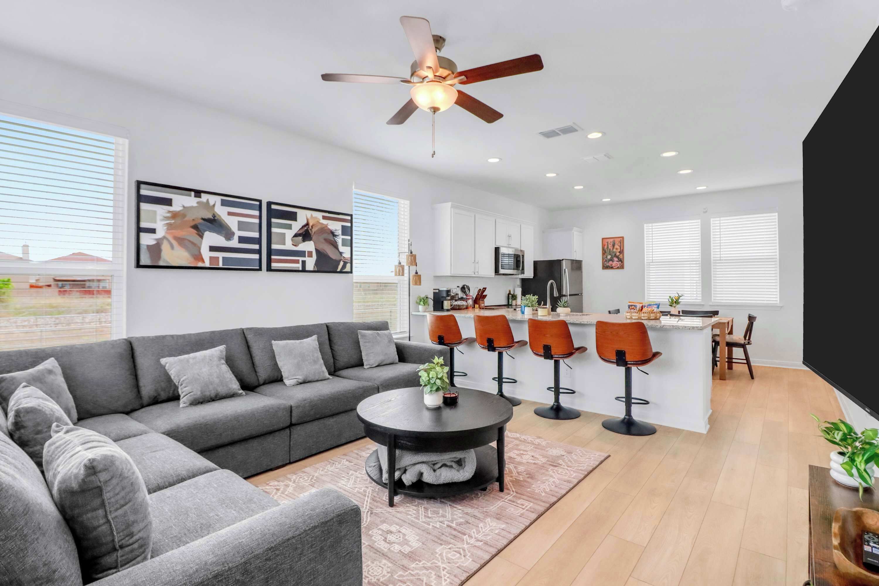 Un salon moderne avec un canapé gris, une table basse ronde et un ventilateur de plafond.