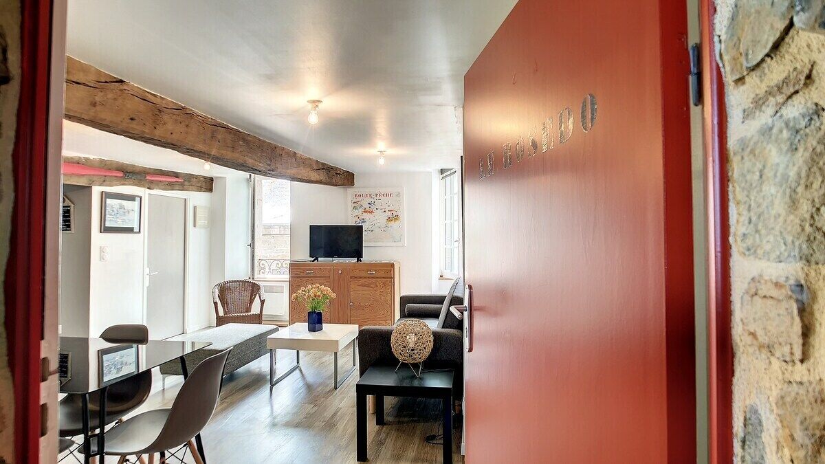 A modern interior with a dining area, a television, and a stone wall.