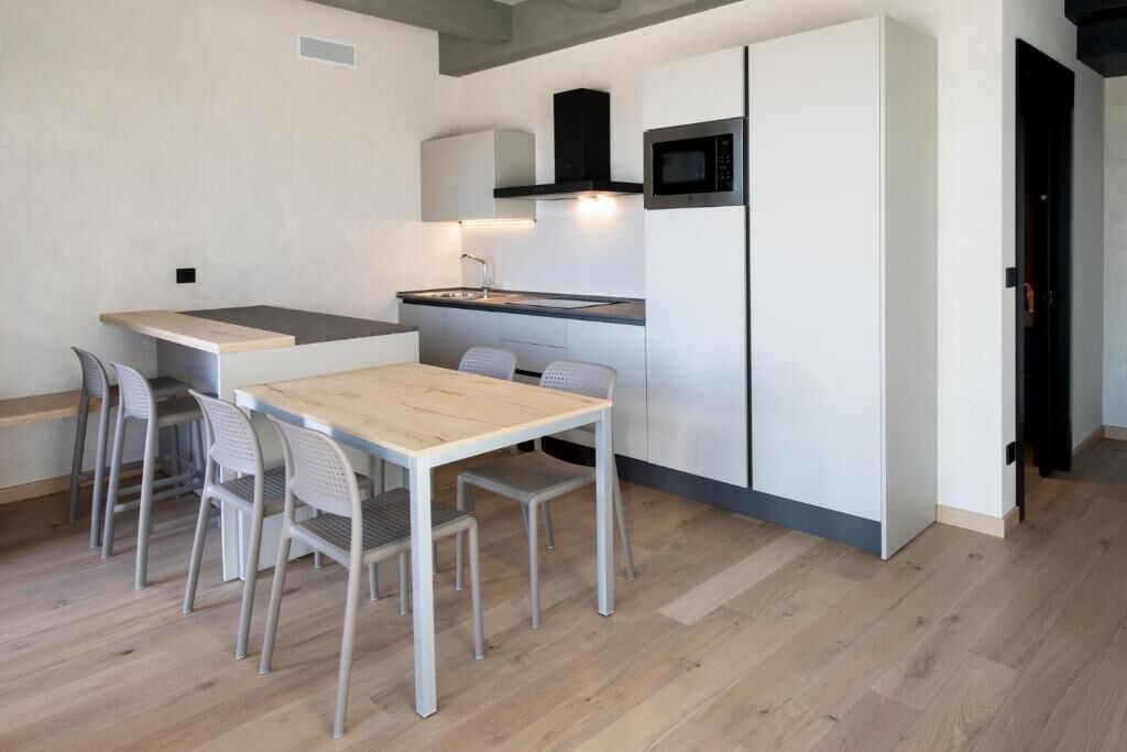 A compact kitchen with a dining table and chairs, a microwave, and a built-in oven.