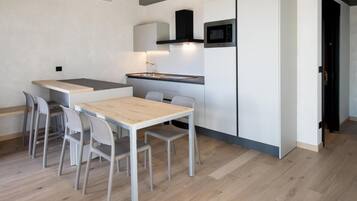 A compact kitchen with a dining table and chairs, a microwave, and a built-in oven.
