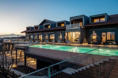 A modern hotel with a swimming pool, outdoor seating, and a view of the mountains.
