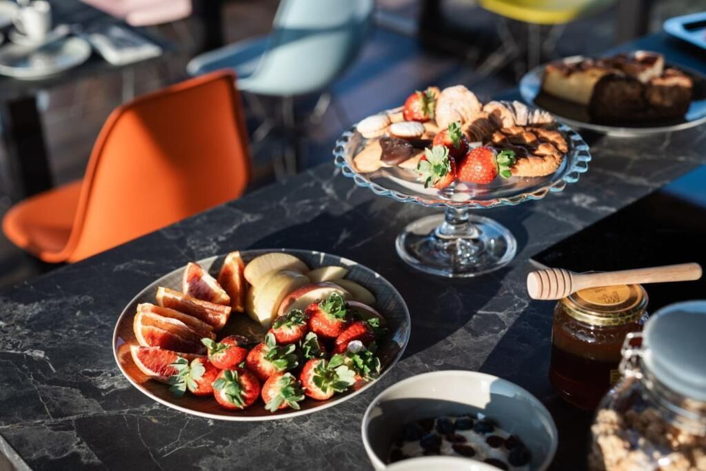 A table with a fruit platter, a dessert display, and a honey jar.