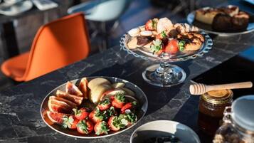 A table with a fruit platter, a dessert display, and a honey jar.