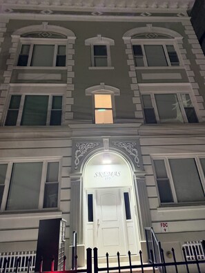 A building with a prominent entrance, a sign above the door, and a fire escape on the right. - Serene 1-bedroom apartment with AC in vibrant Newark (Newark)