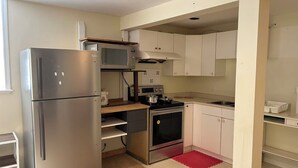 Eine kleine Küche mit Kühlschrank, Mikrowelle, Backofen und Spüle.