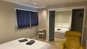 Ein Schlafzimmer mit Bett, Sessel, Schreibtisch und Spiegel.