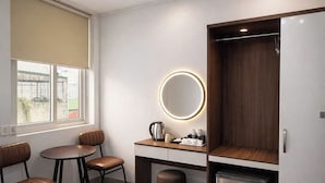 A hotel room with a bed, a desk with a mirror, a coffee maker, a wardrobe, and a trash bin. - Dreamora Centre Hotel (Hanoi)