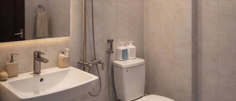 Un baño moderno con lavamanos, inodoro y ducha.