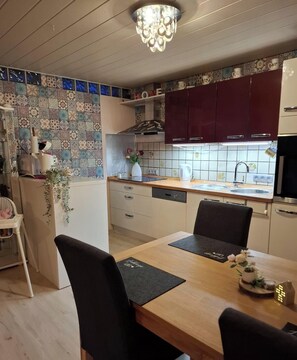 A modern kitchen with a dining area, featuring a chandelier, patterned tiles, and a 'HOME' sign. - Vacation apartment Seeblick in Langweiler (Langweiler)