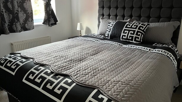 A bedroom with a tufted headboard, patterned bedding, and a window with curtains. - Perfect Spacious & Comfortable 2-bedroom Apartment in Derby for a relaxing stay (Derby)