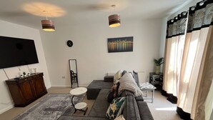 A living room with a sofa, a coffee table, a TV, and a painting on the wall. - Perfect Spacious & Comfortable 2-bedroom Apartment in Derby for a relaxing stay (Derby)