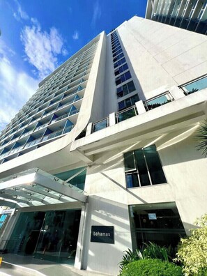 A modern building with a glass facade, a prominent entrance, and a sign reading 'bahamas'.