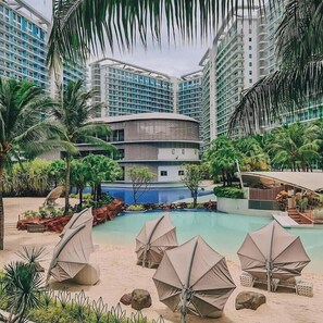 Un complex turístic amb piscina, palmeres i edificis moderns.