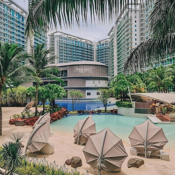 A resort with a pool, palm trees, and modern buildings.