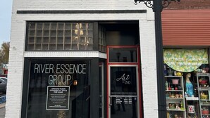 Un immeuble dont le rez-de-chaussée est composé d’un espace commercial à louer, avec une façade noire portant une enseigne indiquant « River Essence Group », et une entrée bien visible.