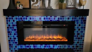 Une cheminée ornée d’une bordure de carreaux bleus, avec le chiffre décoratif « 211 » au-dessus, et une horloge sur le côté droit.