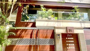 Un edificio moderno con entrada de vidrio, un portón de madera y un letrero con números de habitaciones.