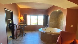 Une salle de bain spacieuse dotée d’une grande baignoire, d’un espace douche et d’une fenêtre laissant entrer la lumière naturelle.