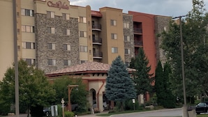 Un hôtel à plusieurs étages, doté d’une façade en pierre, de balcons et d’un espace de stationnement.